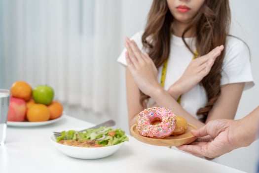 Diet and dieting. Beauty slim female body confuse donut. Woman in exercise clothes achieves weight loss goal for healthy life, crazy about thinness, thin waist, nutritionist. photo