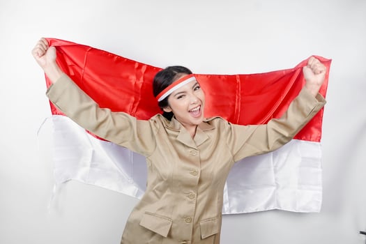 Smiling government worker woman holding Indonesia's flag isolated by white background. PNS wearing khaki uniform. Indonesia's independence day concept. photo