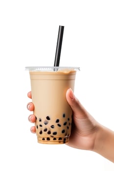 A hand holding takeaway plastic cup of delicious iced bubble milk tea and black pearls isolated on white background. ai generated photo