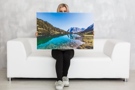 Young girl holds photo canvas at home on the couch