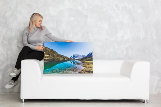 Young girl holds photo canvas at home on the couch