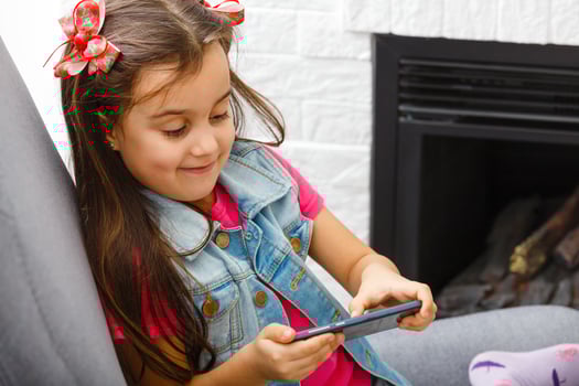 Cute Little girl using mobile phone at home photo