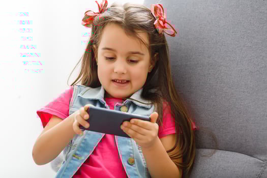 Cute Little girl using mobile phone at home photo