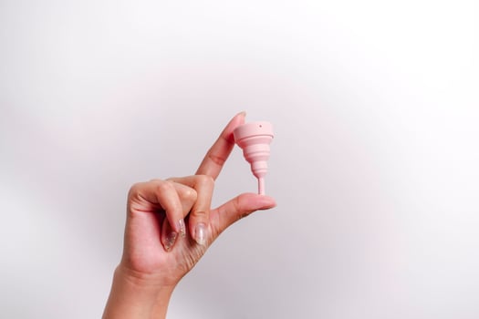 Close up of woman hand holding menstrual cup over white background. Women health concept, zero waste alternatives photo