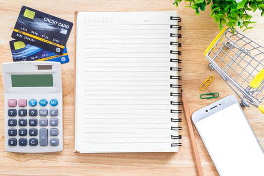 Credit cards,notebook,flower pot tree,smartphone and Shopping cart on wooden background,Online banking Concept,Top view office table. photo
