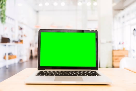 Mockup image of laptop with blank Green screen on wooden table of In the coffee shop. photo