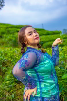 a tea garden farmer is posing beautifully in the middle of green tea leaves photo