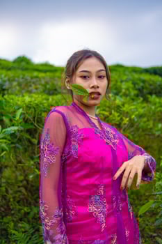 an Asian woman in a pink dress is standing in front of a tea garden photo