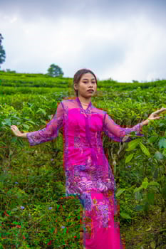 an Asian woman in a pink dress is standing in front of a tea garden photo