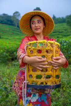 a tea leaf farmer is enjoying the view of the tea garden while holding a basket photo