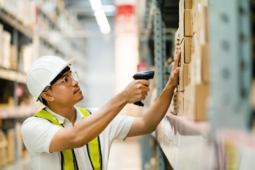 Male warehouse worker scanning barcodes on boxes in a warehouse. Male warehouse worker working with barcode scanner. photo