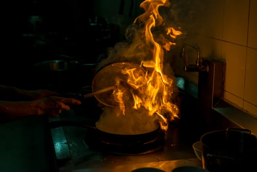 Chef cooking and doing flambe on food in restaurant kitchen photo