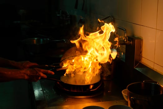 Chef cooking and doing flambe on food in restaurant kitchen photo