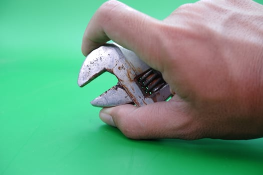 hand holding a wrench over a green background. photo