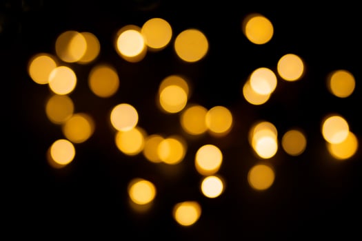 Yellow and brown defocused lights on black background. Blurred bokeh, overlay. Christmas, New Year, holiday photo