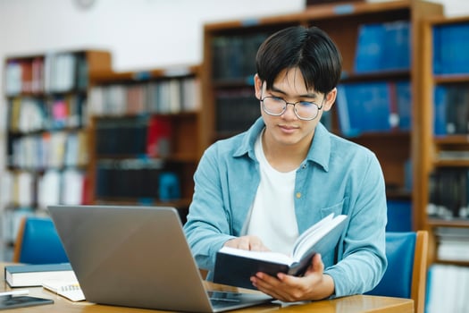 Young university student using laptop for online learning, searching and learning at library. photo
