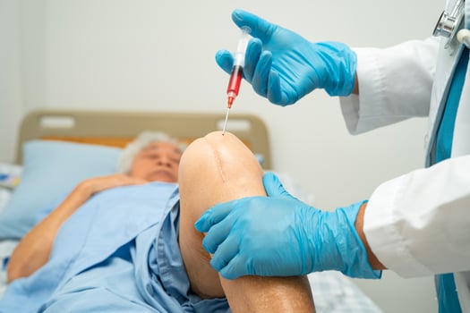 Asian doctor inject Hyaluronic acid platelet rich plasma into the knee of senior woman to walk without pain. photo