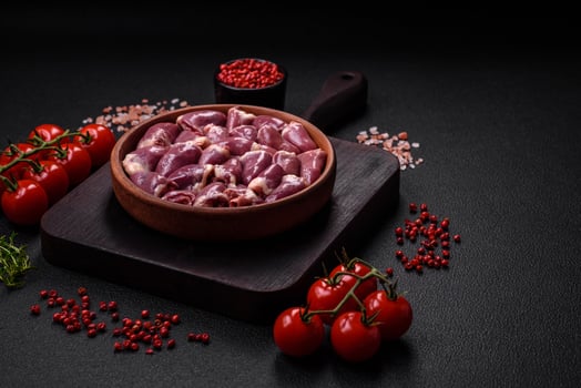Fresh raw chicken or turkey hearts in a ceramic plate with salt, spices and herbs photo