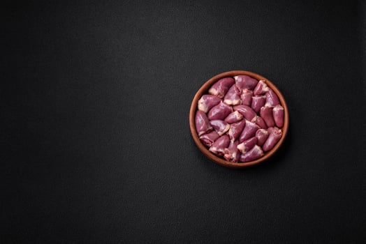 Fresh raw chicken or turkey hearts in a ceramic plate with salt, spices and herbs photo