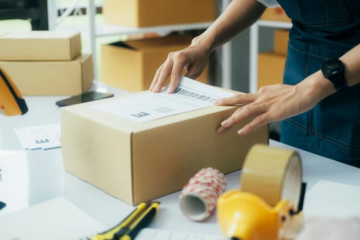 Young business owner putting shipping label on parcel. photo