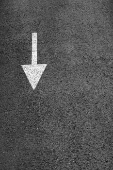 White arrow on the dark gray asphalt. photo