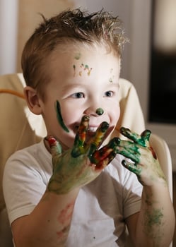 Excited little boy playing with finger paints photo