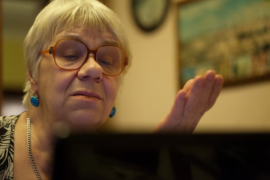 Senior woman gesturing as she reads on laptop photo