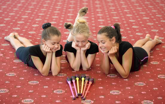 Three girls on the floor looking at Indian clubs photo
