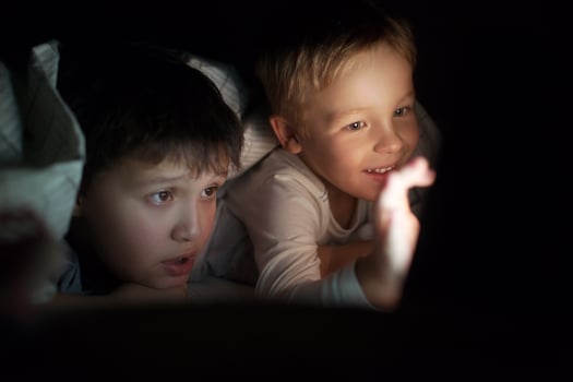 Two boys watching movie or cartoon on pad at night photo
