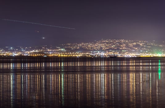 Light streak in sky over city at night photo