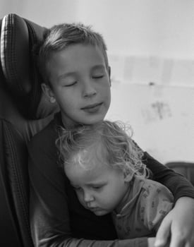 Loving brother comforting baby sister in hugs photo