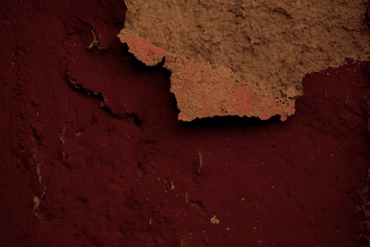 Detail of flaking plaster on a dark red wall photo