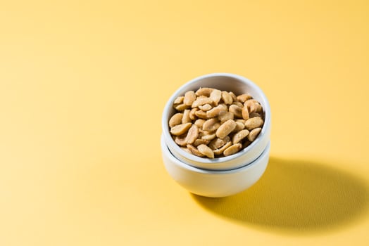 Salted peanuts in a white bowl on a delt background in hard light. Healthy modern vegetarian food. photo