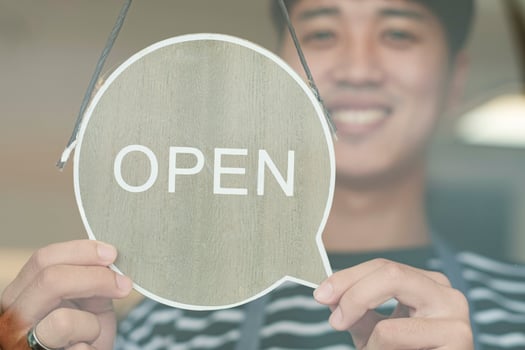 Happy Coffee Shop owner in an apron turning open sign board on glass door. Small business owner opening a small business. photo