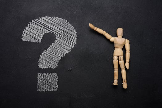 A wooden mannequin and a white chalk-drawn question mark on a black board, depicting the concept of uncertainty and curiosity photo
