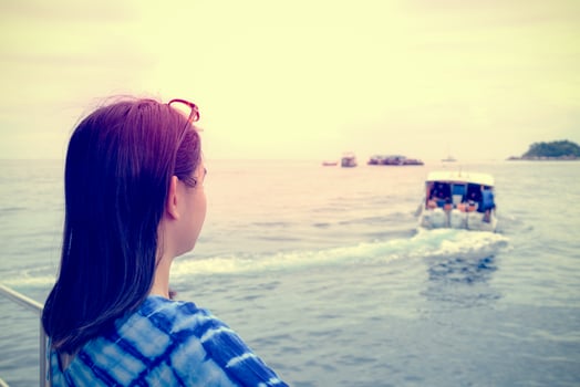 Woman looking at the boat that sailed away from her in vintage style photo