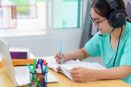 Asian woman writing notes at book learning online photo
