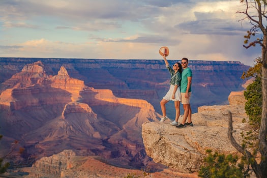 Happy young couple on a steep cliff taking in the amazing view over famous Grand Canyon on a beautiful sunny day, Grand Canyon National Park, Arizona, USA photo