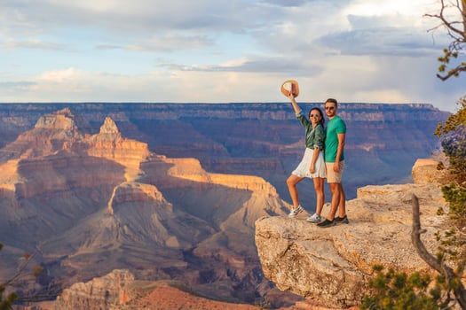Happy couple on a steep cliff taking in the amazing view over famous Grand Canyon on a beautiful sunset, Grand Canyon National Park, Arizona, USA photo