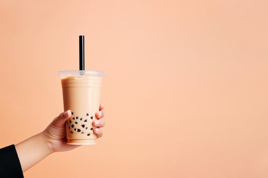 A hand holding takeaway plastic cup of delicious iced bubble milk tea and black pearls with copy space. ai generated photo