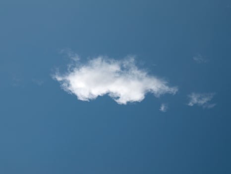 Single white cloud over blue sky background. Fluffy cumulus cloud shape photo