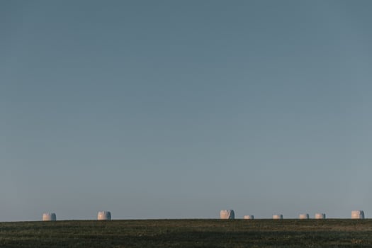 Bales of straw wrapped in plastic on horizon during sunrise photo
