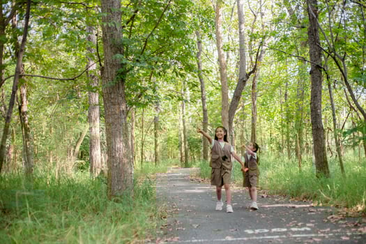 Asian little girls explore nature through magnifying glasses and binoculars in the park. Education, field trips, research, and discovery concepts. photo