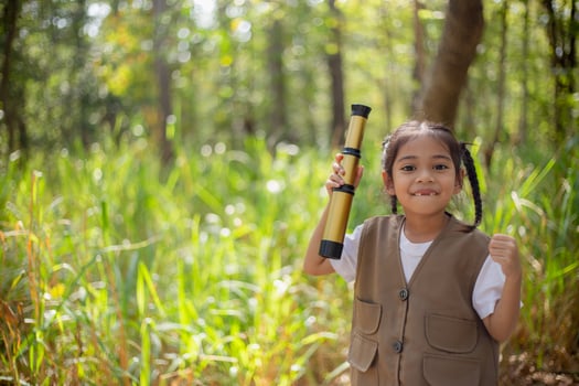 Asian little girls explore nature through magnifying glasses and binoculars in the park. Education, field trips, research, and discovery concepts. photo