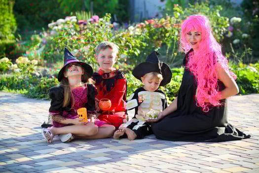 Young kids trick or treating during Halloween . Children and a woman are sitting on the road in halloween costumes. photo