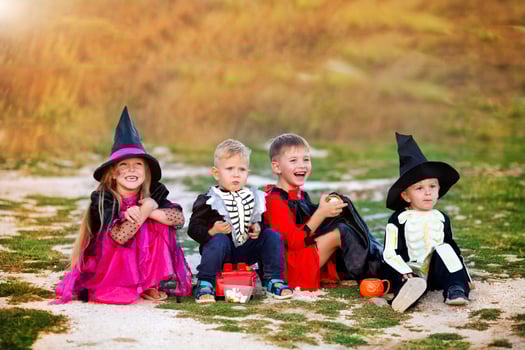 Young kids trick or treating during Halloween . Children are sitting on the road in halloween costumes. photo