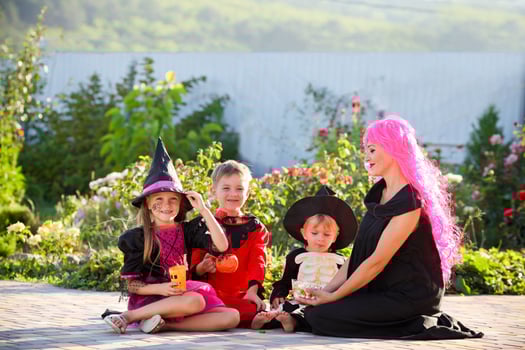 Young kids trick or treating during Halloween . Children and a woman are sitting on the road in halloween costumes. photo