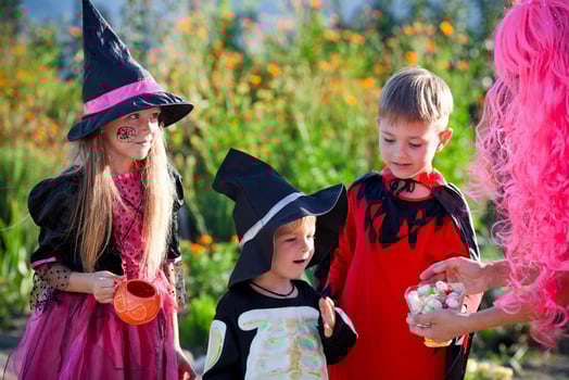 Group children trick or treat in Halloween costume . A little boys and a girl in suits  receive  candy from a woman  . photo