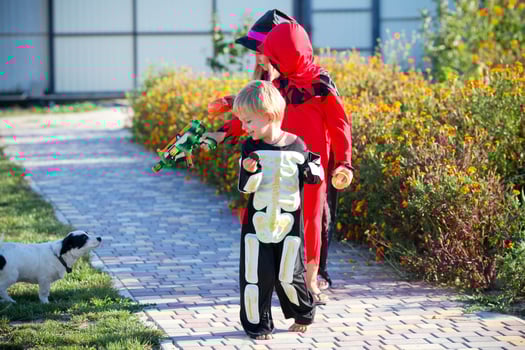 Children in halloween costumes pretend to shoot a dog. photo