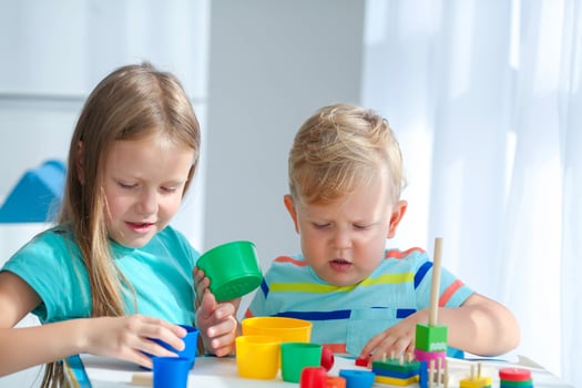 Sister helps little brother to assemble the pyramid. Educational logical toys for children. Montessori games for child development. photo